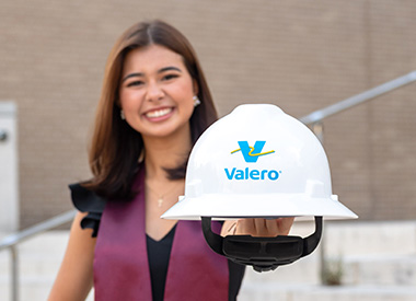 A college graduate holds a Royal Dutch Shell hard hat.